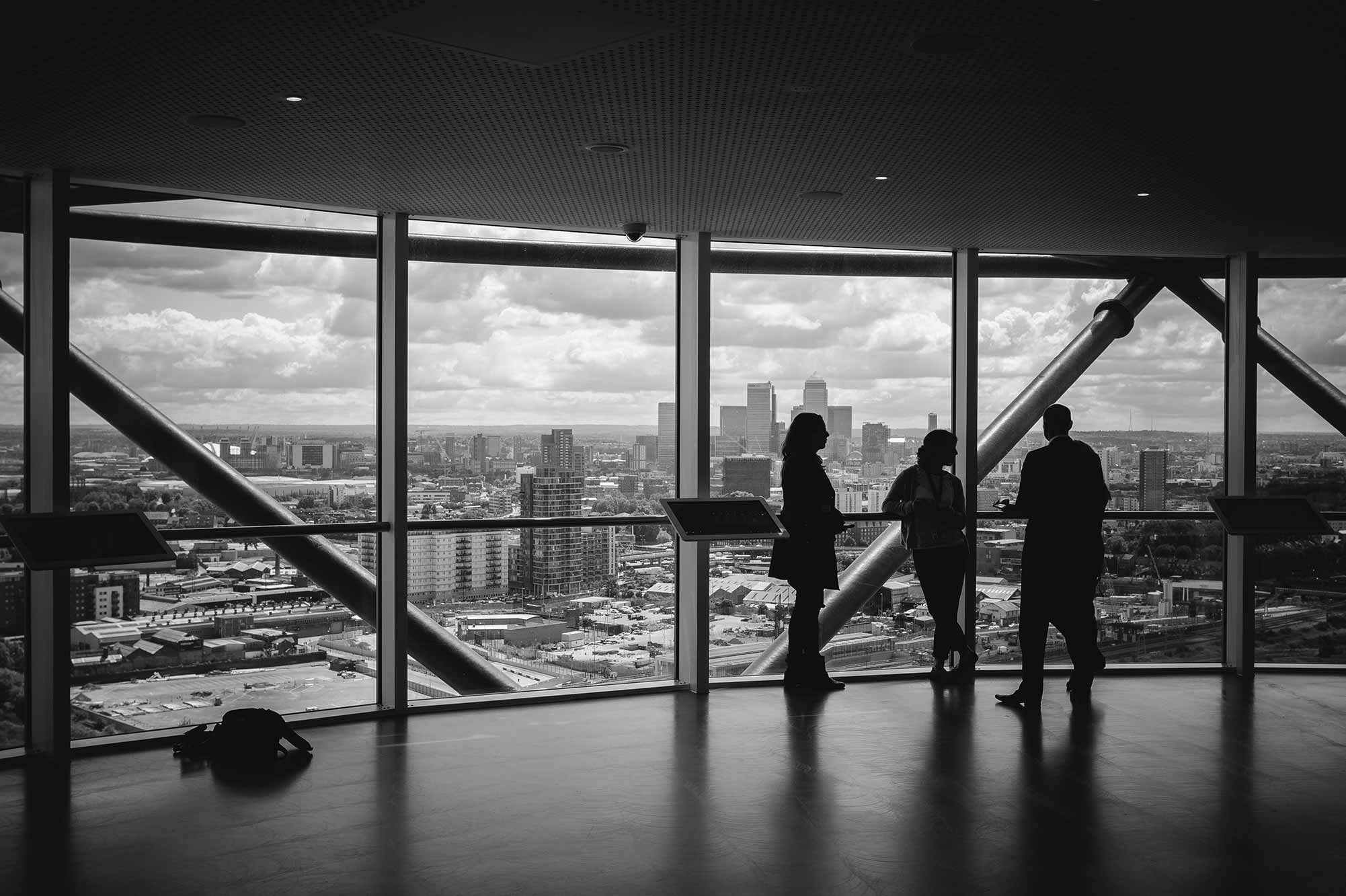 People standing against window with city behind